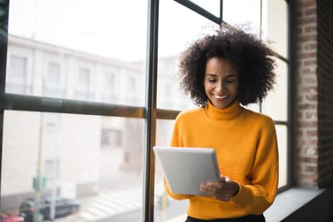 Woman in orange smiling at tablet